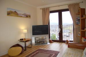 ein Wohnzimmer mit einem Flachbild-TV und einem Balkon in der Unterkunft Ty Pen y Bryn in Dolgellau in Dolgellau