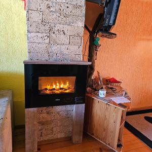 a fireplace in the corner of a living room with a fire at "Athos"apartment potkrovlje in Višegrad