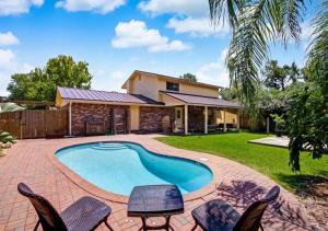 a backyard with a swimming pool and chairs and a house at Grand 3 BD 2 BA House With Pool in Jacksonville Beach