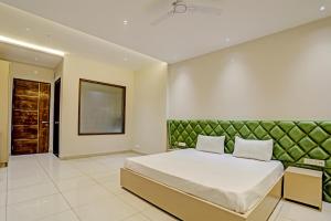 a bedroom with a large bed with a green headboard at OYO Miraas Hotel And Banquet Hall in Ludhiana
