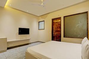 a bedroom with a bed and a flat screen tv at OYO Miraas Hotel And Banquet Hall in Ludhiana