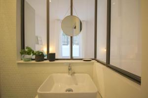 La salle de bains est pourvue d'un lavabo blanc et d'un miroir. dans l'établissement In the heart of Old Lille: Rue de la Monnaie, à Lille