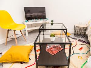 uma sala de estar com uma mesa de café em vidro e uma cadeira amarela em Budget studio near Paris em Gennevilliers
