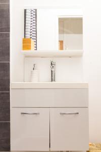 uma casa de banho branca com um lavatório e um espelho em Budget studio near Paris em Gennevilliers