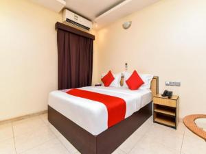 um quarto de hotel com uma cama grande com almofadas vermelhas em OYO Royal Plaza Residence -3 em Ras al-Khaimah