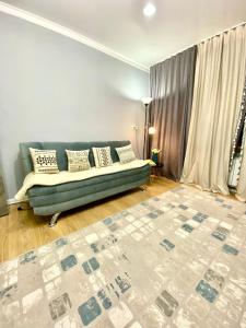 a living room with a green couch and a rug at 3-x комнатная квартира в ЖК Евразия в самом сердце Алматы! in Almaty +39 photos