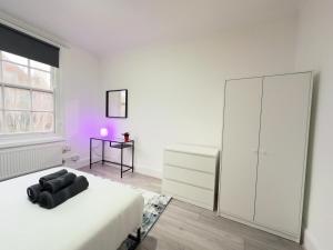 a white bedroom with a bed and a dresser at The Chalton Funk-in Kings Cross (ZONE 1)!!! in London