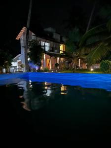 a swimming pool in front of a house at night at Backwater Brook in Kumarakom +7 photos