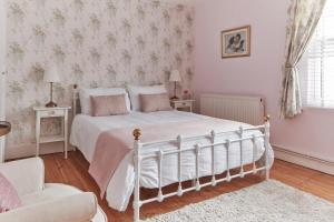 um quarto com uma cama branca e um sofá em Spacious coastal cottage close to beach - Bailey Cottage em Deal