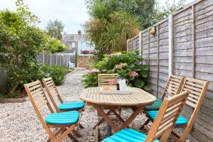 uma mesa de madeira e cadeiras num jardim em Spacious coastal cottage close to beach - Bailey Cottage em Deal