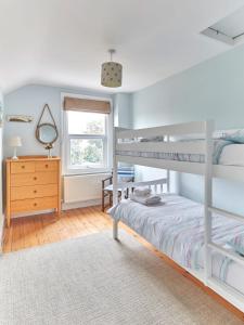 a bedroom with two bunk beds and a dresser at Spacious coastal cottage close to beach - Bailey Cottage in Deal