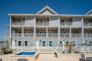 a large white apartment building with a swimming pool at Beach Life in Port Aransas