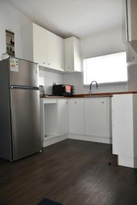 a kitchen with white cabinets and a stainless steel refrigerator at Cabaña de campo in Valdivia