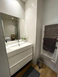 a white bathroom with a sink and a mirror at Les Belles Feuilles Appartement in Paris