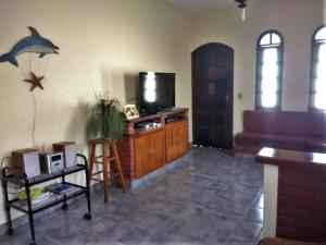 uma sala de estar com televisão e um golfinho na parede em Casa com piscina em Bertioga