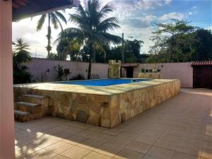 ein Pool mit einer steinernen Mauer um ihn herum in der Unterkunft Casa com piscina in Bertioga