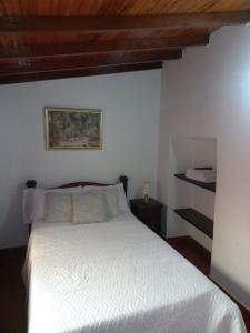 a bedroom with a white bed with a wooden ceiling at Real Dream Hostel in San Gil