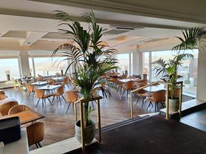 a restaurant with tables and chairs and potted plants at Hotel Noordzee in Katwijk +44 photos