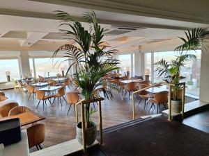 a restaurant with tables and chairs and potted plants at Hotel Noordzee in Katwijk