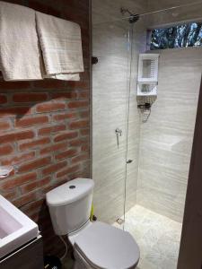 a bathroom with a toilet and a glass shower at El refugio del Guayacán in Manizales
