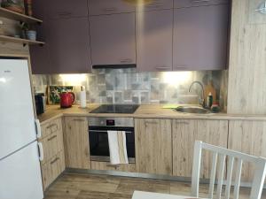 a kitchen with wooden cabinets and a sink and a stove at Apartament KLARA in Rumia