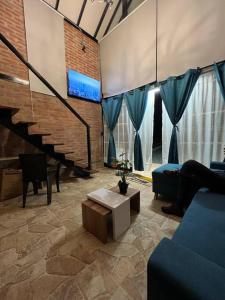 sala de estar con sofá, mesa y escaleras en El refugio del Guayacán, en Manizales