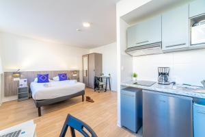 图卢兹Montempô + Apparthôtel Toulouse Cité Internationale的房间里有一间带床的卧室和一间厨房