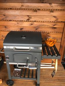 a grill sitting on a stand next to a wooden wall at Słoneczna Polana nad Biebrzą in Goniadz
