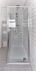 a shower with a glass door in a bathroom at Sunbeam Cottage in Deal