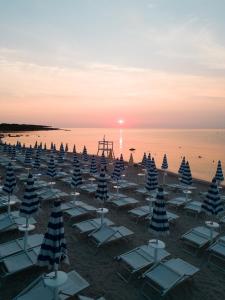 a group of chairs and umbrellas on a beach at MClub Budoni in Budoni