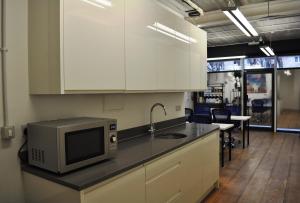 eine Küche mit weißen Schränken und einer Mikrowelle auf der Theke in der Unterkunft Cosmos capsule coworking London in London