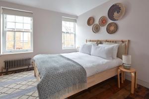 a bedroom with a bed with white sheets and two windows at Two Rows Back From the Sea in Deal