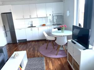 a kitchen with white cabinets and a table and a tv at Villa LA in Landskrona