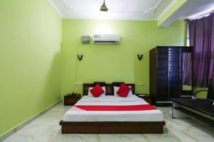 1 dormitorio con 1 cama con paredes verdes y almohadas rojas en OYO Hotel Alfa, en Amb