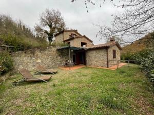una casa de piedra con dos sillas delante en La Casella antico feudo di campagna, en Ficulle