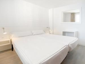 Habitación blanca con cama y espejo en Apartamentos Morito Beach, en Cala Millor