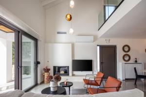 a living room with a couch and a tv at Villa Venetiko - Refined Minimalist Villa with Sunset Bliss by etouri in Chania
