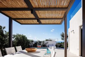 a patio with a table and chairs and a wooden pergola at Villa Venetiko - Refined Minimalist Villa with Sunset Bliss by etouri in Chania