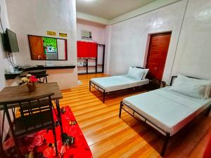 uma sala de estar com duas camas e uma mesa em Monte Rio Gardens Bed & Breakfast em Alaminos