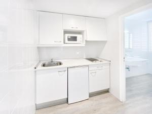 eine weiße Küche mit einer Spüle und einer Mikrowelle in der Unterkunft Apartamentos Morito Beach in Cala Millor
