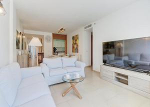 a living room with white furniture and a large flat screen tv at Apt Ca na Claire in Port de Pollensa