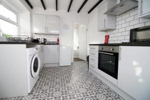 a white kitchen with a washer and dryer at Herbert House by StayStaycations in Treorky
