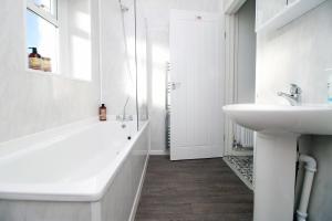 a white bathroom with a sink and a bath tub at Herbert House by StayStaycations in Treorky