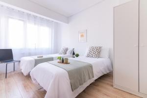 um quarto branco com 2 camas e um sofá em Tetuan street apartment em Santander