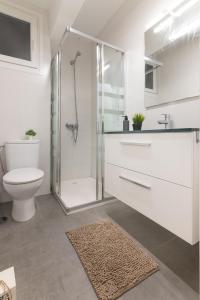uma casa de banho branca com um chuveiro e um WC. em Tetuan street apartment em Santander