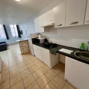 a kitchen with white cabinets and a tiled floor at Thubaneau St Charles Canebière Vieux port in Marseille