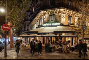 een groep mensen die 's nachts voor een restaurant lopen bij Studio de Charme de Verneuil in Parijs