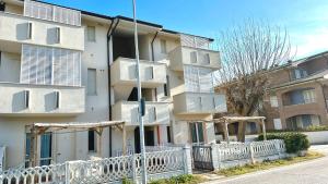 een appartementencomplex met een wit hek ervoor bij F001 - Fano, trilocale con portico a 30mt dal mare in Marotta