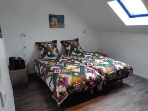 uma cama com um edredão colorido num quarto em à deux pas d'Etretat em Bordeaux-Saint-Clair
