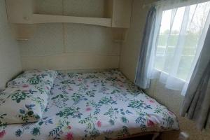 a bed with a floral comforter and a window at Domek 6-os w Campark Service " Zielony Zakątek " in Mrągowo